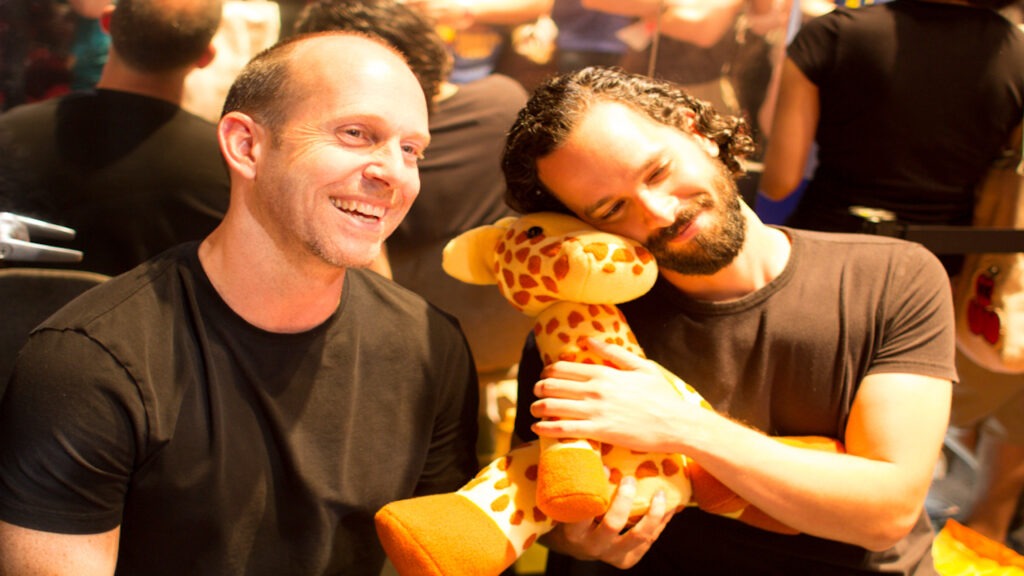 Bruce Straley e Neil Druckmann mentre abbracciano una giraffa di The Last of Us
