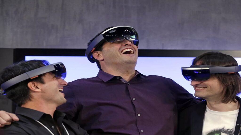 Tre dirigenti di Microsoft mentre ridono con dei visori della VR