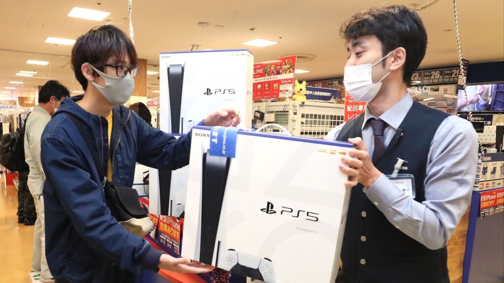 Due giocatori giapponesi con una scatola di PS5 in mano