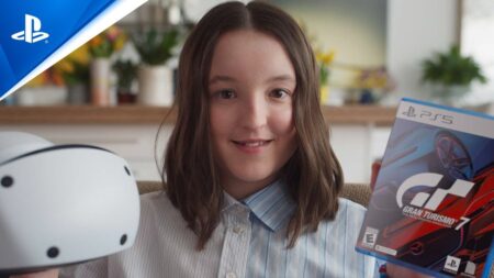 Bella Ramsey in primo piano con il PlayStation VR2 ed una copia di Gran Turismo 7 in mano