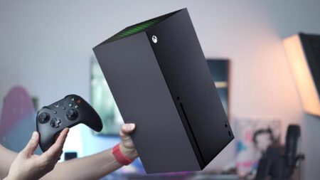 Una Xbox Series X in primo piano sorretta da una mano