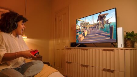 Una ragazza che indossa le cuffie Xbox con una televisore ed una Xbox Series S davanti