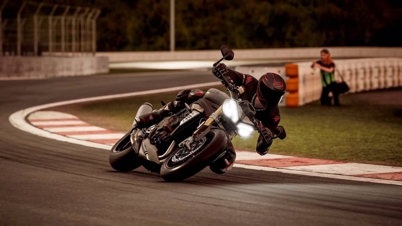 Pilota affronta curva con moto da corsa cittadina, in piega, durante gara serale