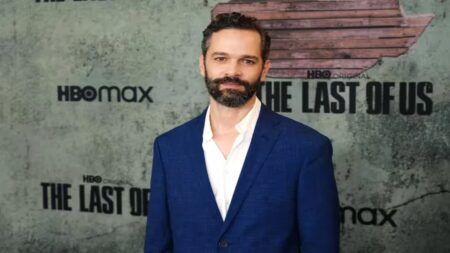 Neil Druckmann con dietro il logo di The Last of Us