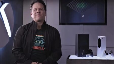 Phil Spencer seduto e sorridente con al fianco una Xbox Series X ed una Series S