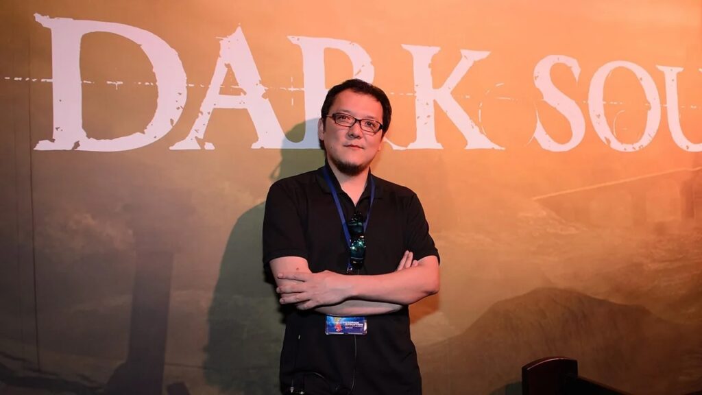 Hidetaka Miyazaki con dietro il logo di Dark Souls