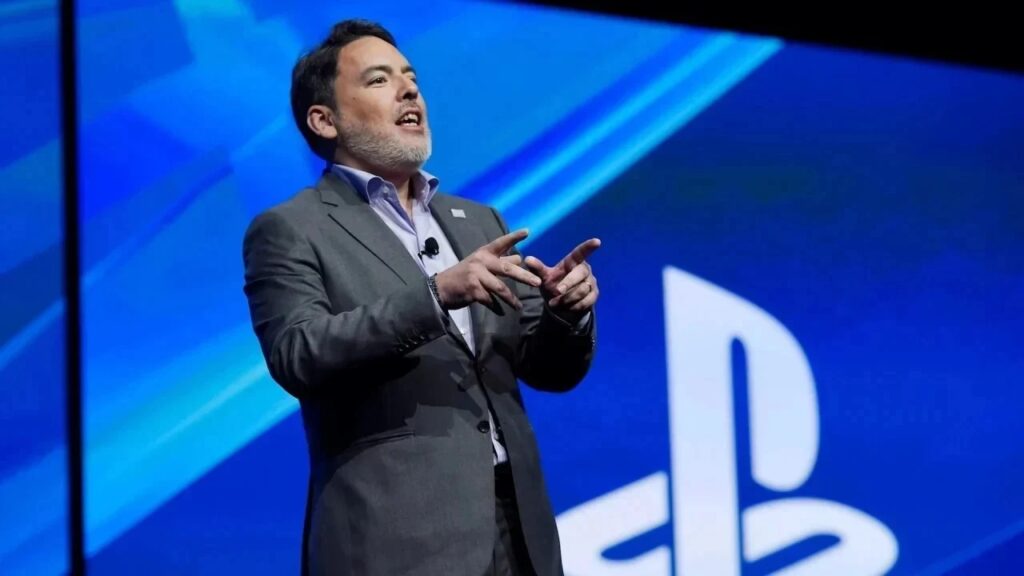 Shawn Layden con dietro il logo di PlayStation