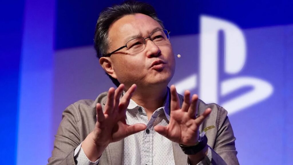 Shuhei Yoshida con dietro il logo di PlayStation