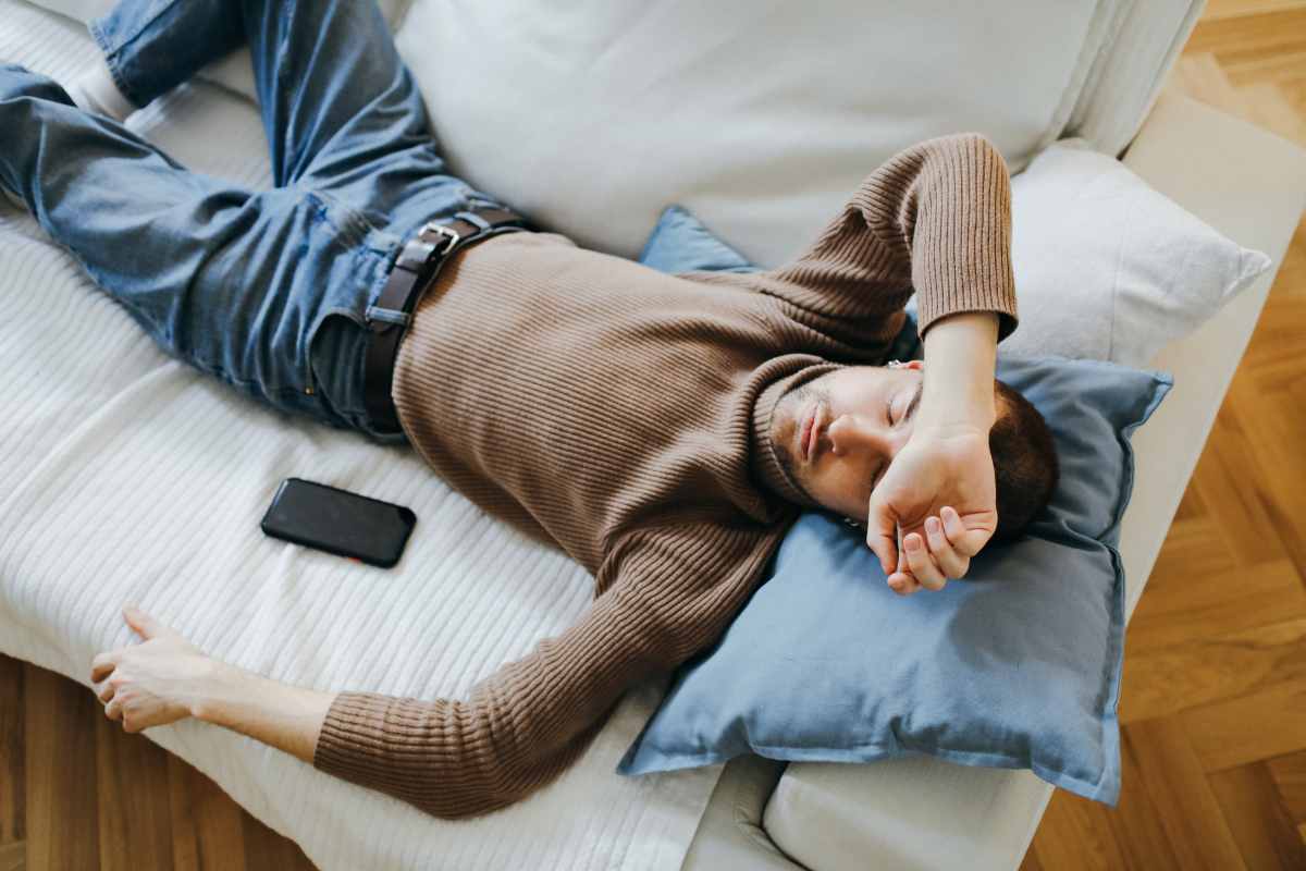Ragazzo che dorme sul divano vicino al cellulare