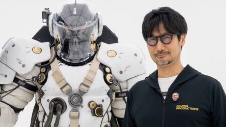 Una statua di Ludens di Kojima Productions con a fianco Hideo Kojima