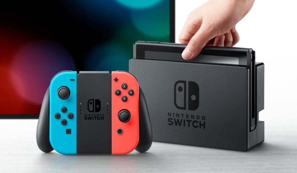 Un Nintendo Switch con dietro un televisore